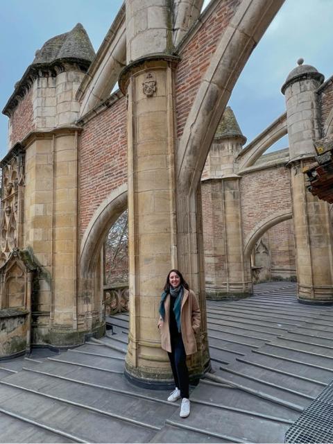 Gabriela Chitwood posing on top of of the Toulouse Cathedral in France, the Cathedral looks enormous while she is smiling at the camera. 