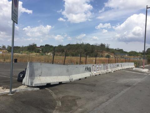 The words "Let us live" are spray painted on a concrete barricade.