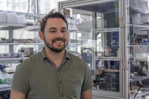 A man stands in lab surrounded by 3D printers.