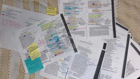 Printed pages of text show color-coded markups by a student performing text analysis.